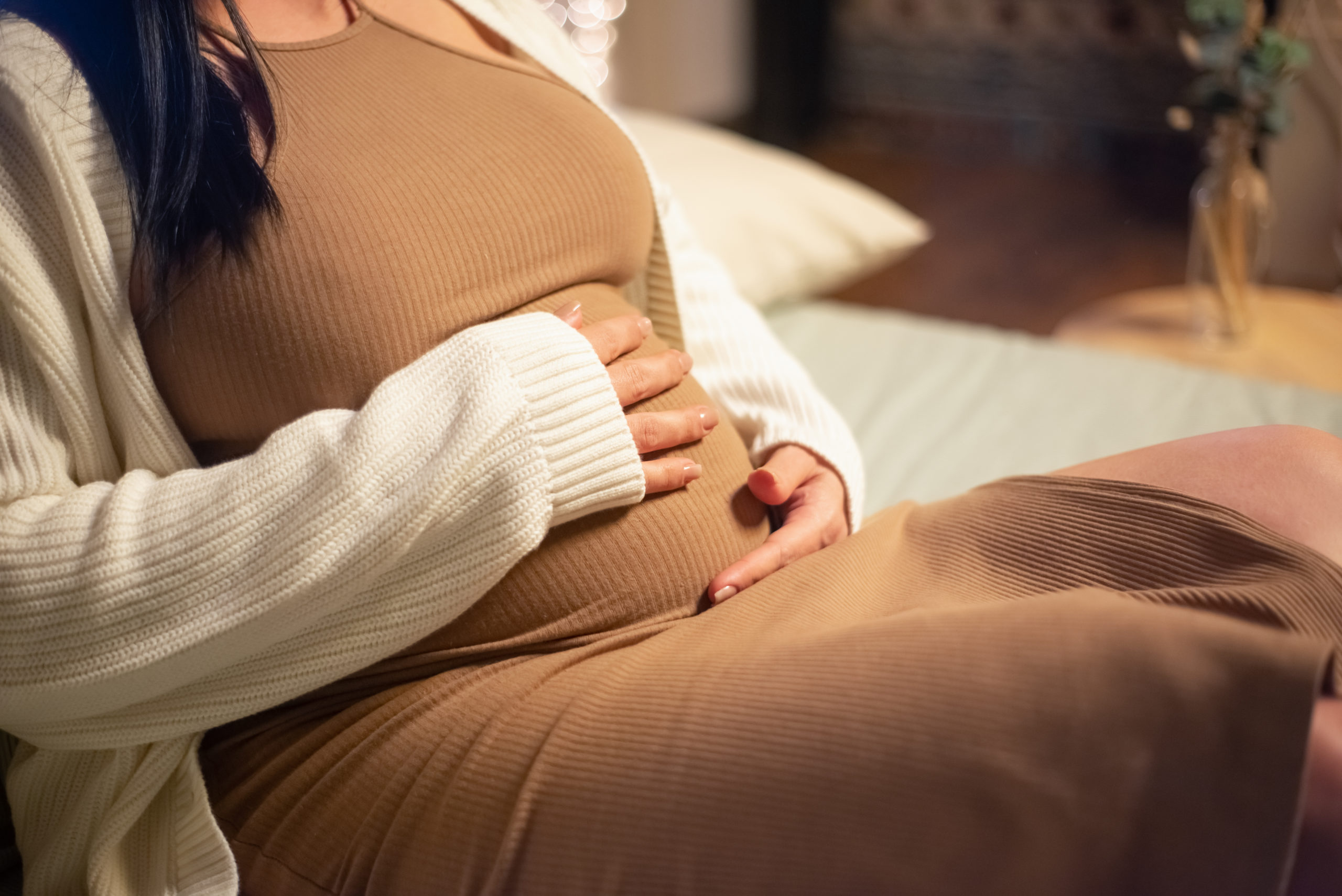 Femme enceinte sans visage se tenant le ventre.